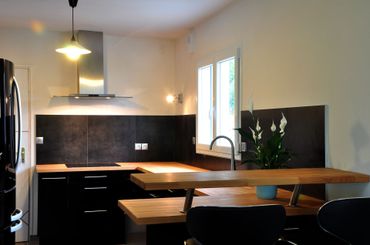 Cuisine moderne avec placards noirs, îlot en bois et suspension lumineuse Cuisine moderne avec placards noirs, îlot en bois et suspension lumineuse