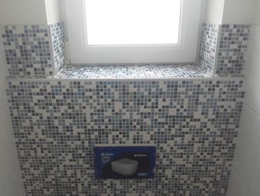 Mur carrelé de mosaïques avec un appui de fenêtre et une petite étagère encastrée au centre. Mondeville Mur carrelé de mosaïques avec un appui de fenêtre et une petite étagère encastrée au centre.
