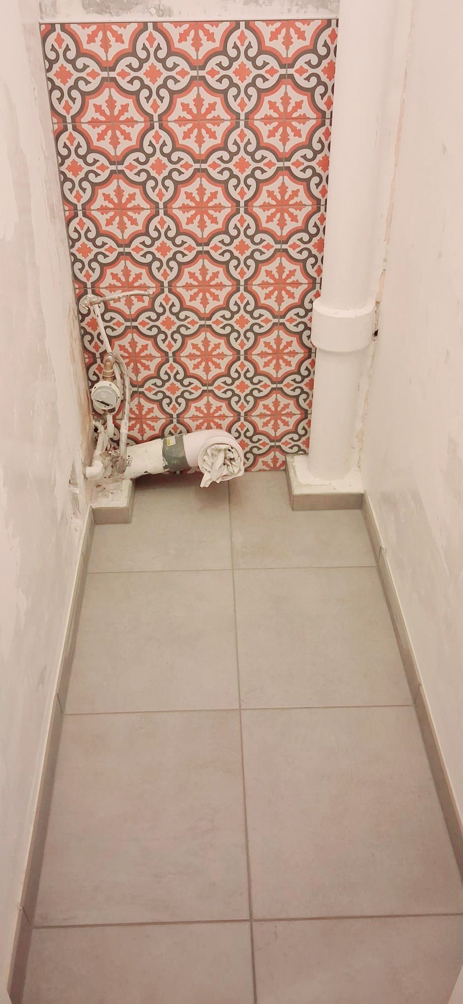 Petit chien debout près d'un rideau à motifs dans un couloir carrelé étroit