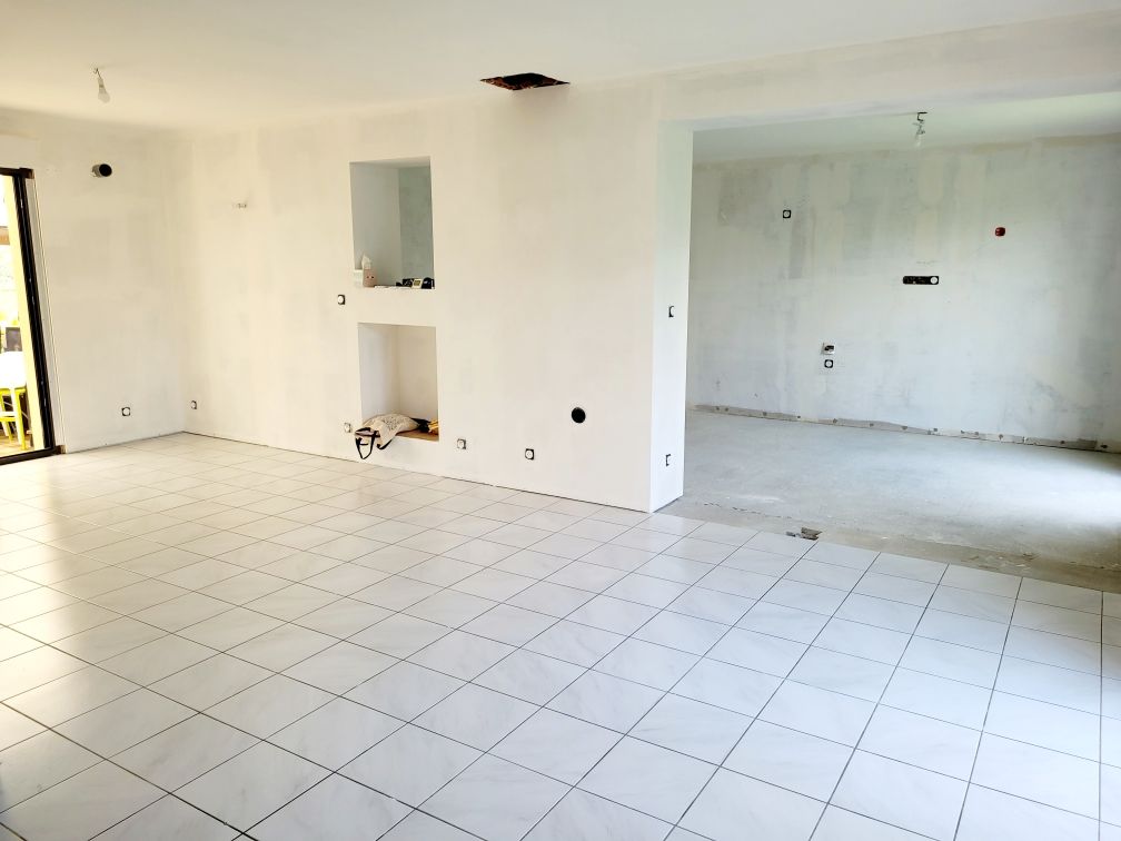 Pièce vide carrelée de blanc avec des niches murales ouvertes et une grande porte donnant sur une autre pièce