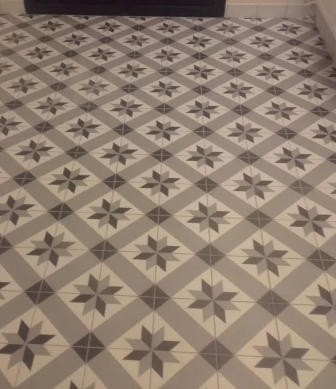 Carrelage à motifs géométriques dans les tons beige, gris et marron foncé.