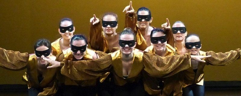 Groupe de danseuses en jaune avec un loup noir