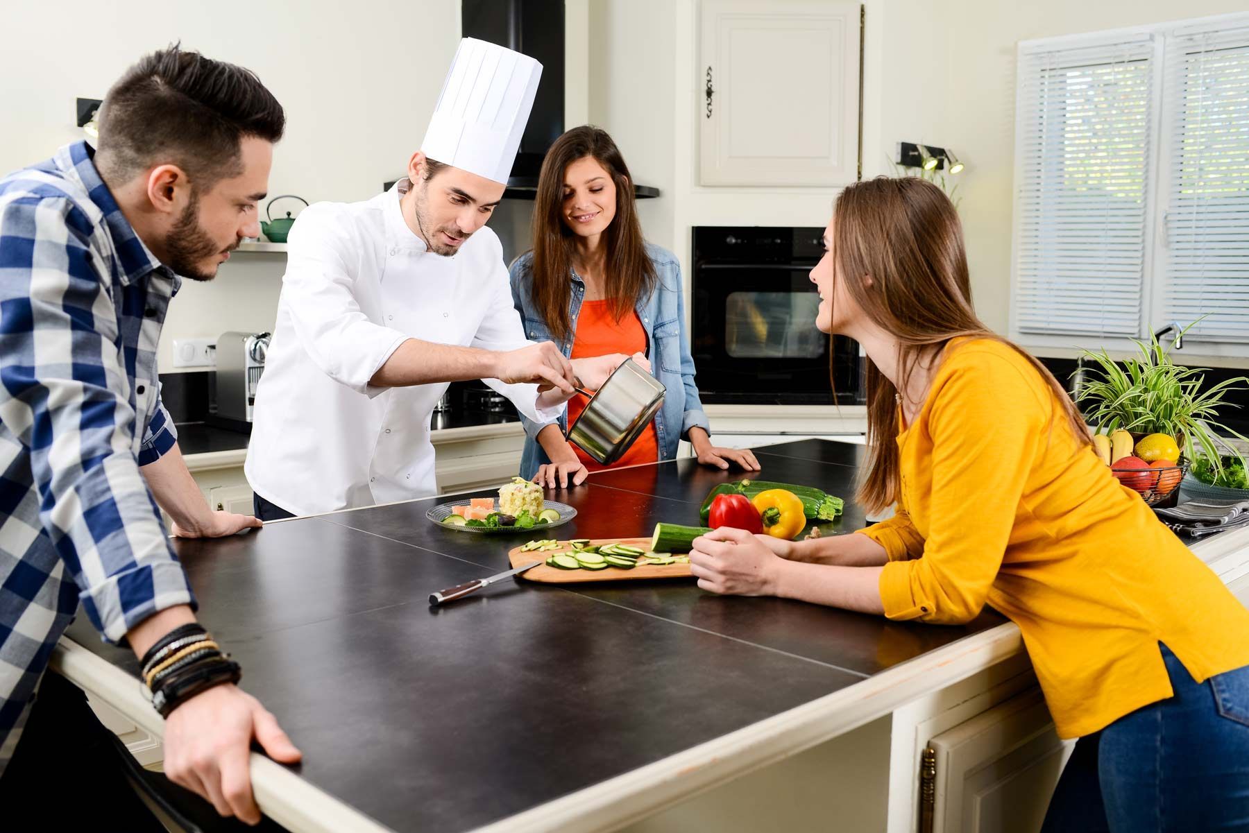Un chef cuisinié avec une toque préparant un plat à domicile