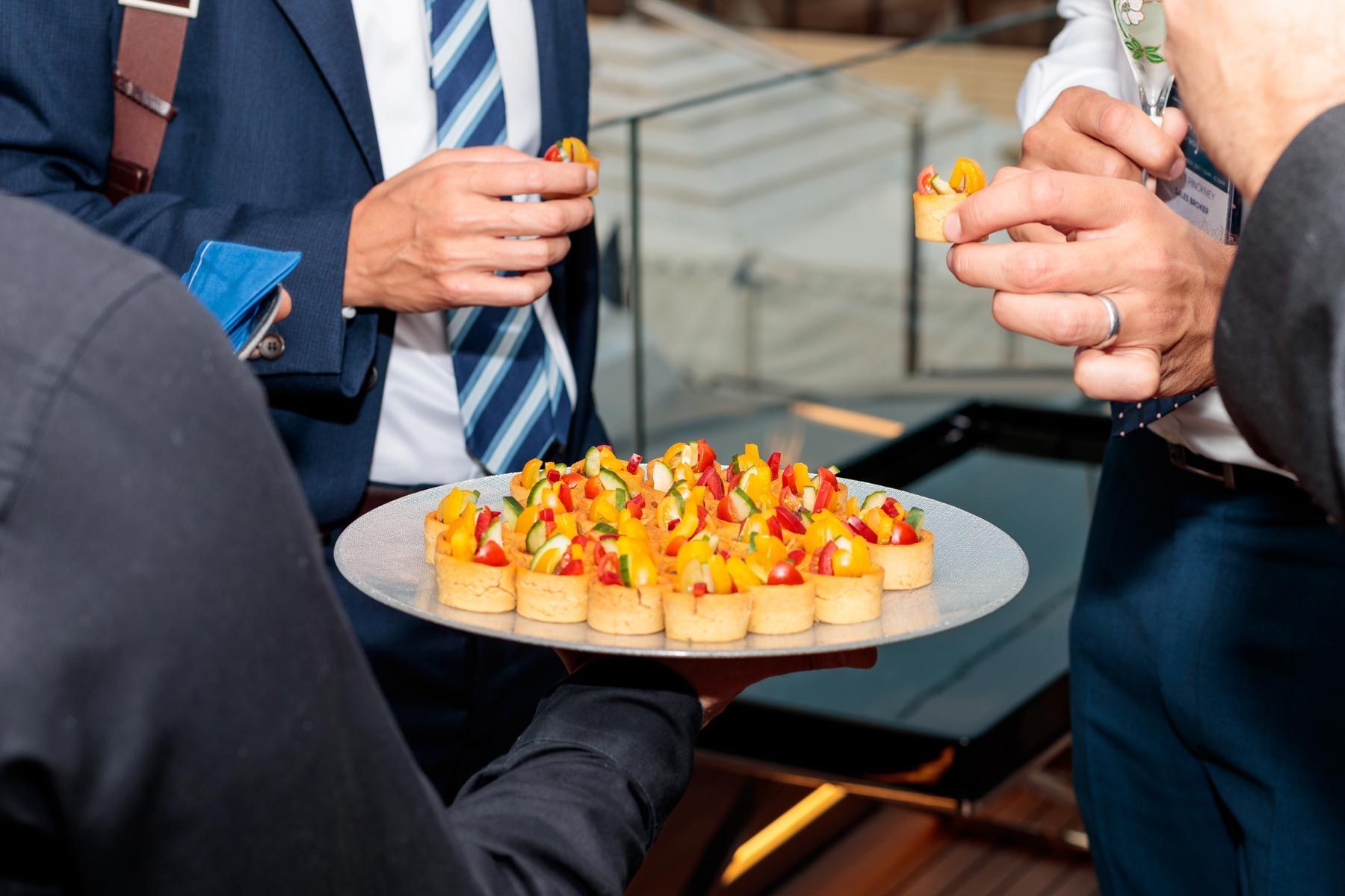 Serveur proposant un apéritif sur assiette à des personnes en costume cravate