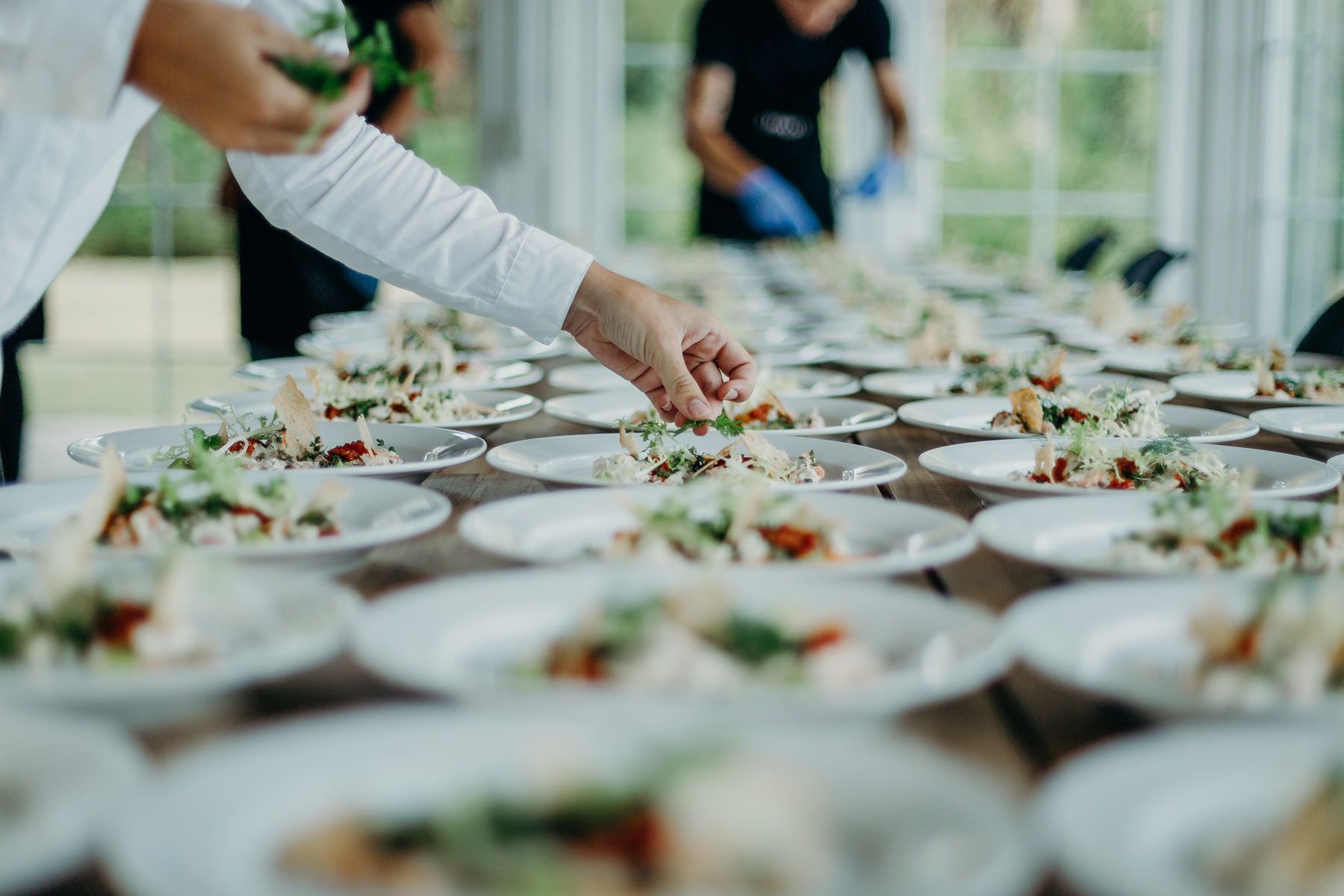 Un serveur plaçant une brindille de plante aromatique sur une plat d'un buffet