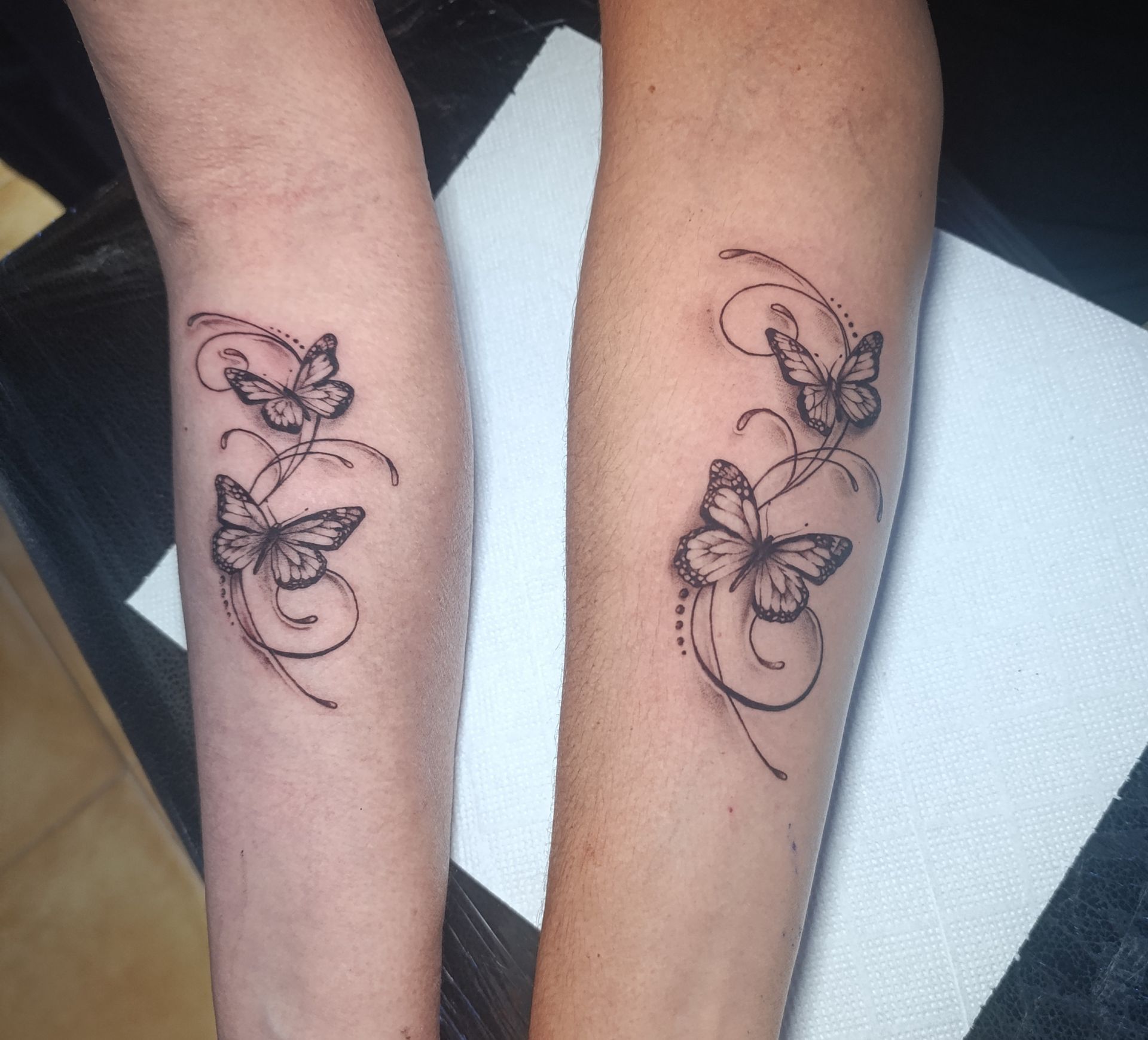 Dos personas tienen mariposas tatuadas en sus antebrazos.