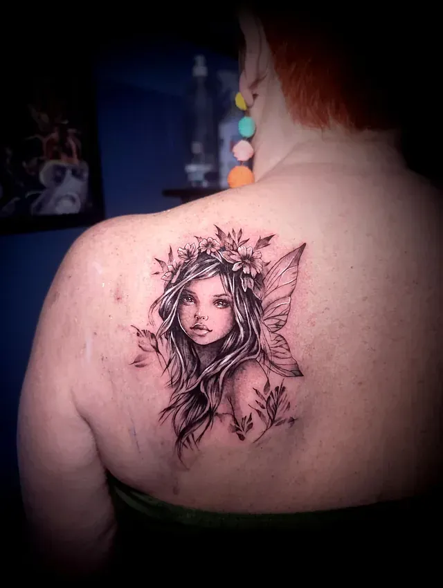Una mujer tiene un tatuaje de un hada en la espalda.