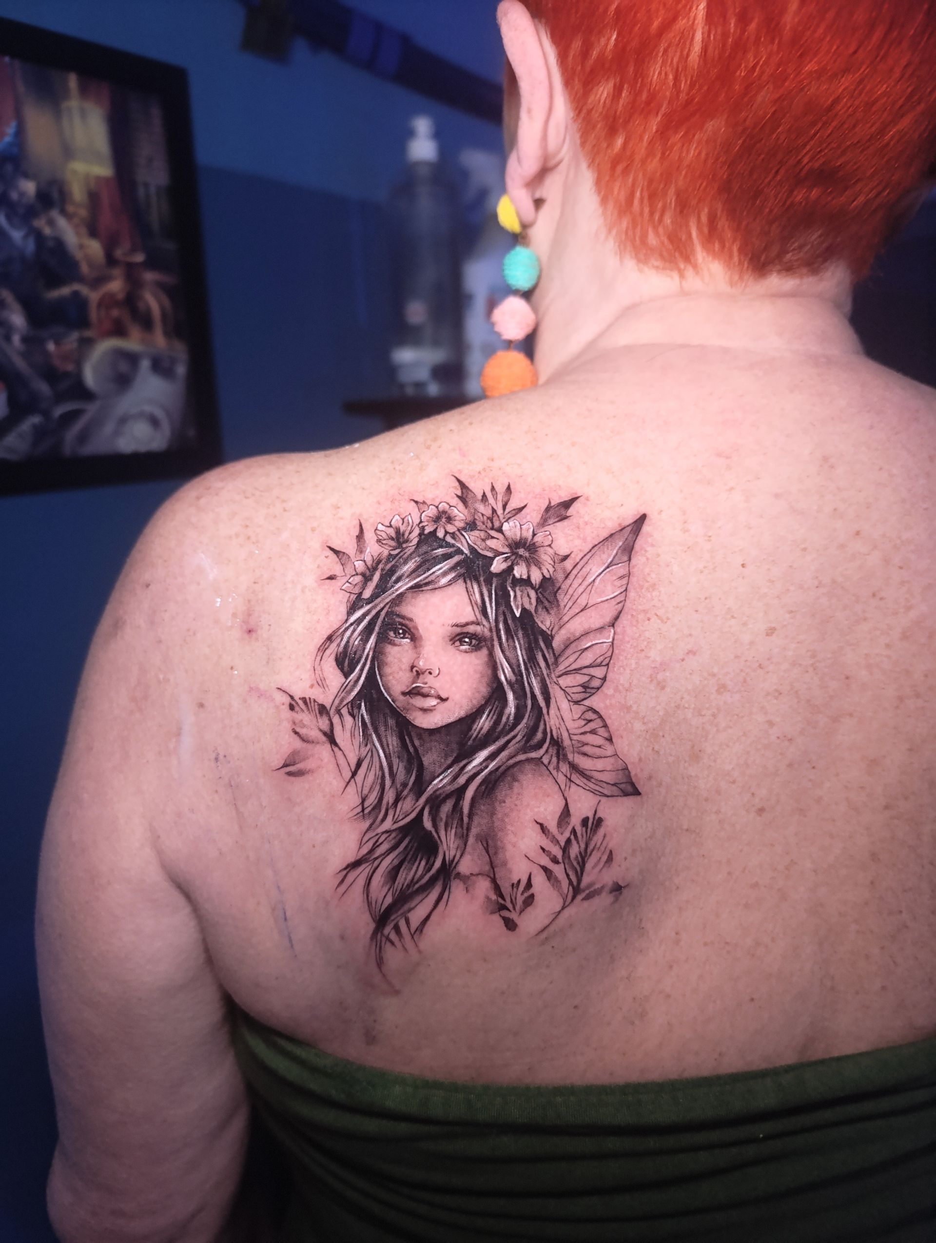 Una mujer tiene un tatuaje de un hada en la espalda.