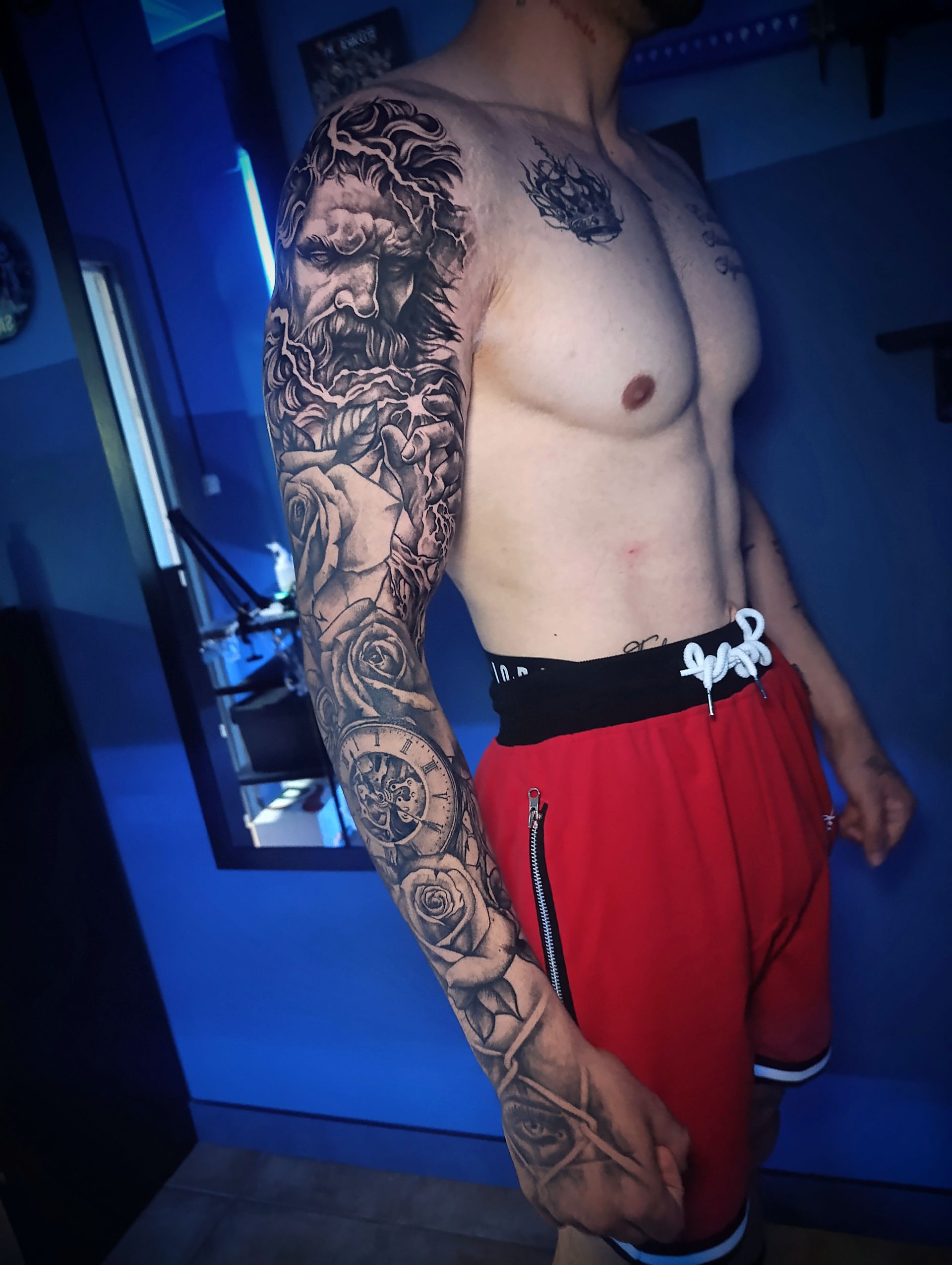 Un hombre sin camisa con un tatuaje en el brazo.