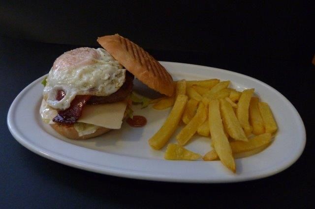 Un plato blanco cubierto con una hamburguesa y papas fritas