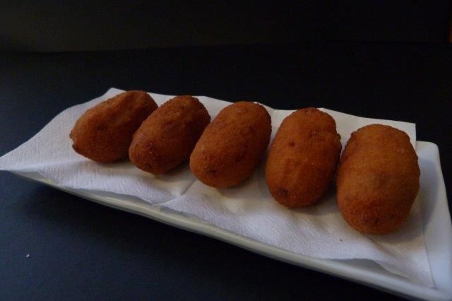 Cuatro bolas de comida frita en un plato blanco sobre una servilleta