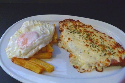 Un plato de comida con un huevo frito y papas fritas