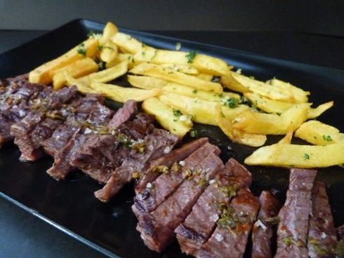 Un plato negro cubierto con bistec y papas fritas