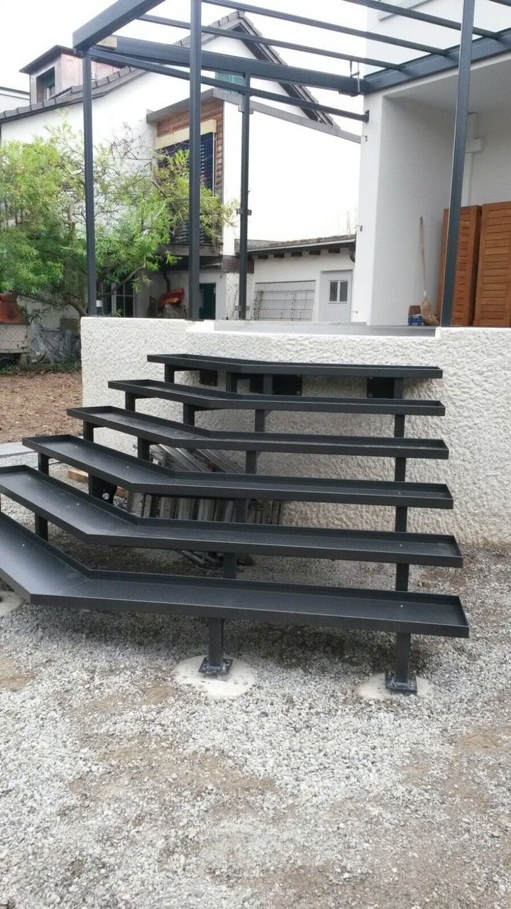 Eine Wendeltreppe aus Metall mit Geländer vor blauem Himmel