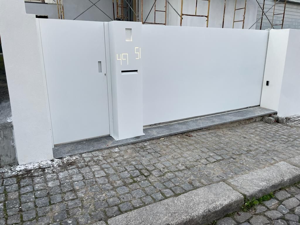 A white gate is sitting on the side of a cobblestone street.