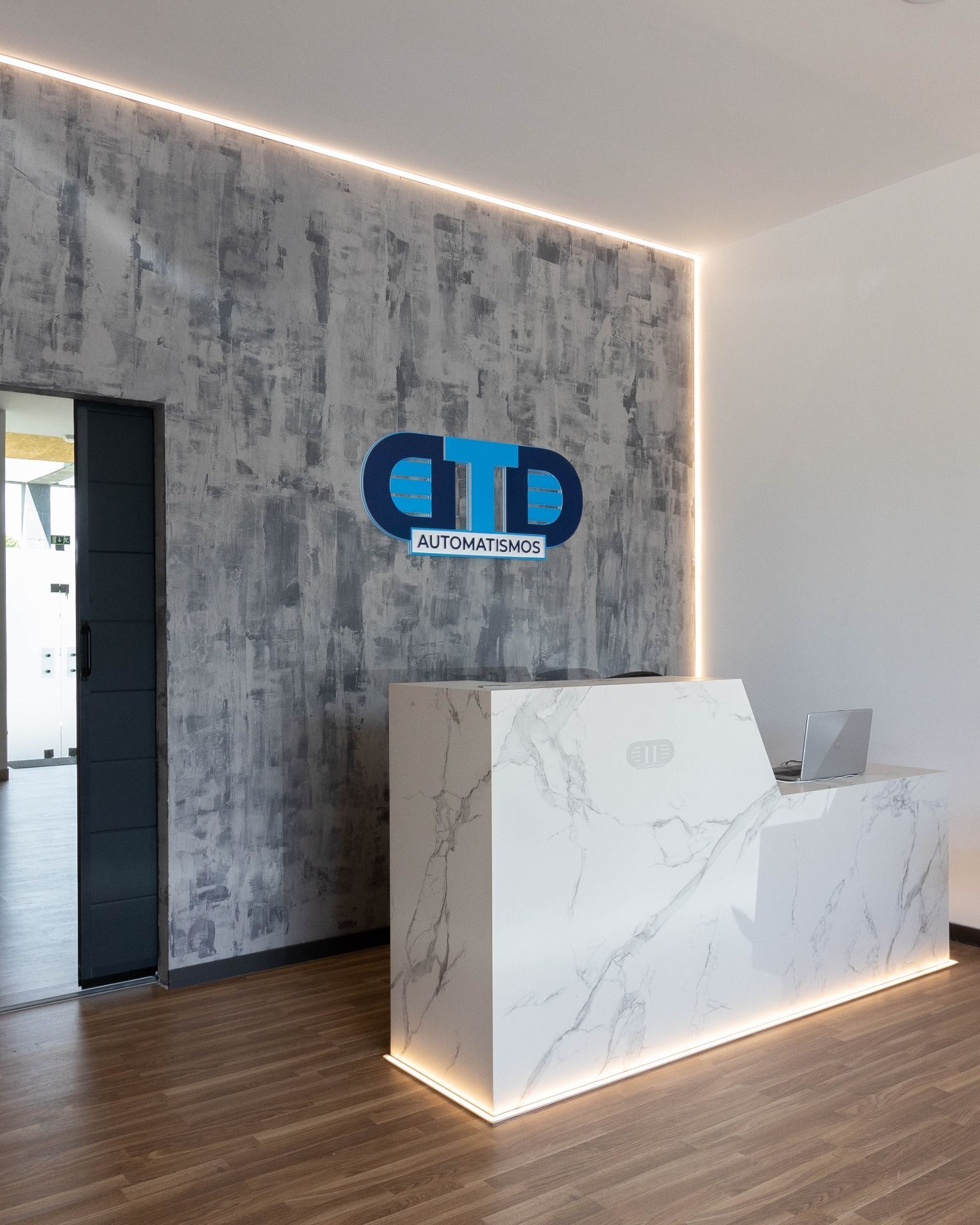 A reception area with a marble counter and a logo on the wall.