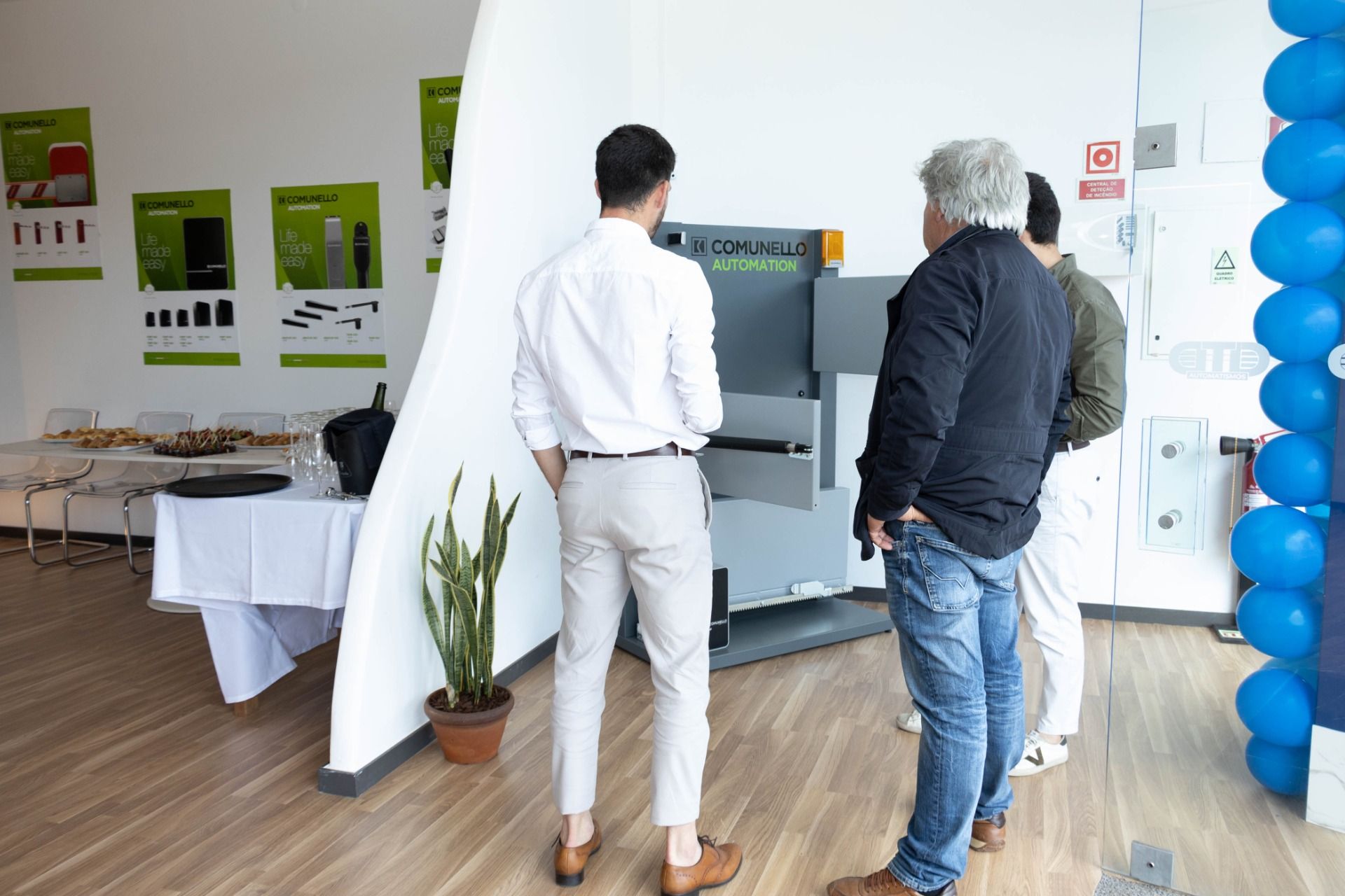 Three men are standing in a room looking at a machine.