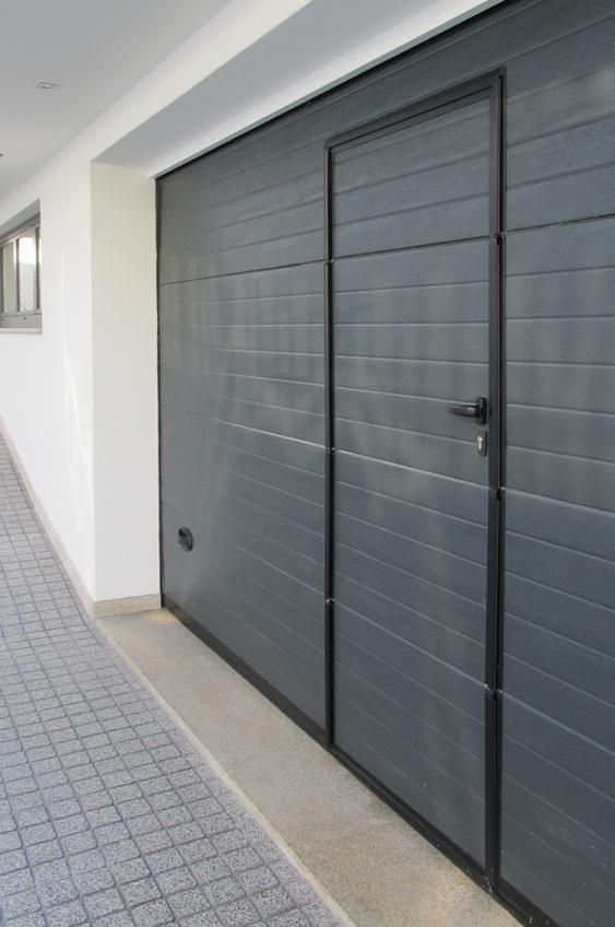 A gray garage door is open in a hallway.