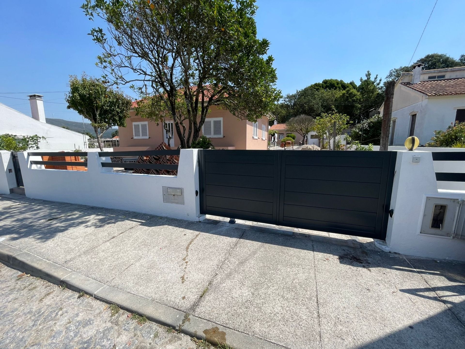A white fence with a black gate in front of a house