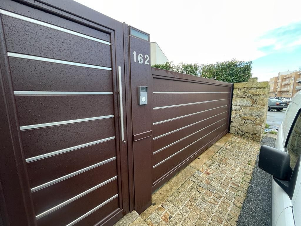 A white car is parked in front of a brown gate.