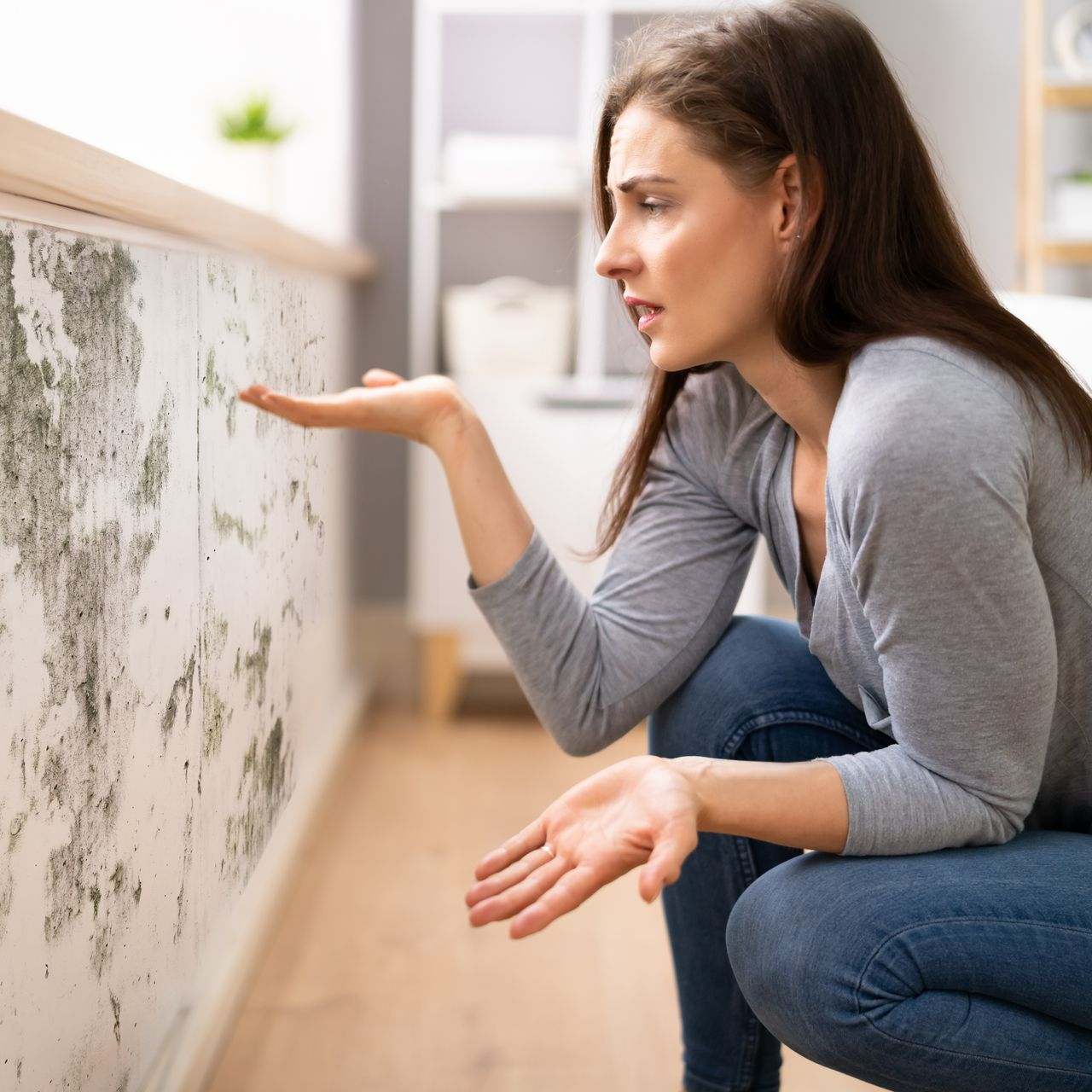 Une femme constatant des taches d'humidité sur un mur