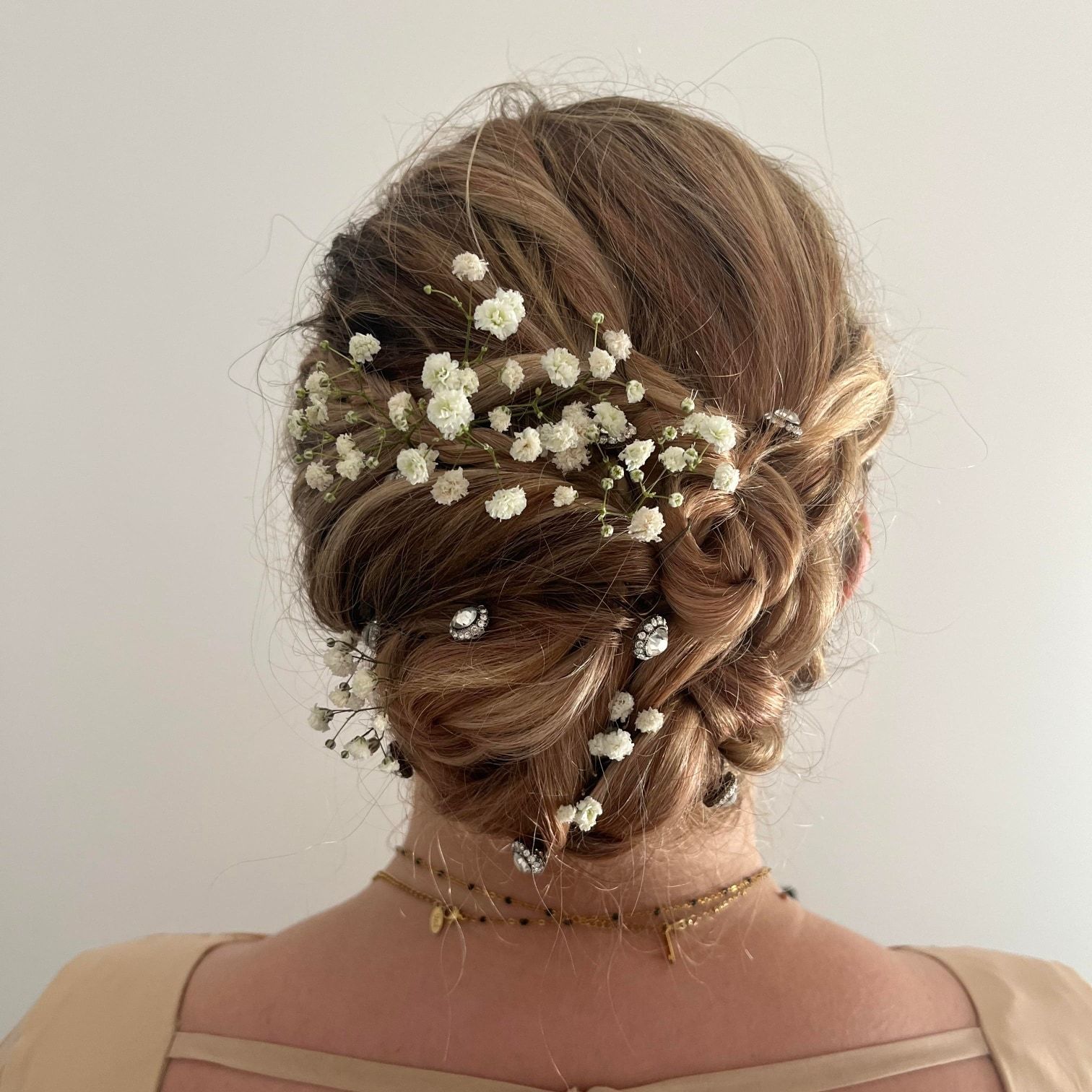Chignon bas orné de fleurs de gypsophile blanches à l'arrière de la tête