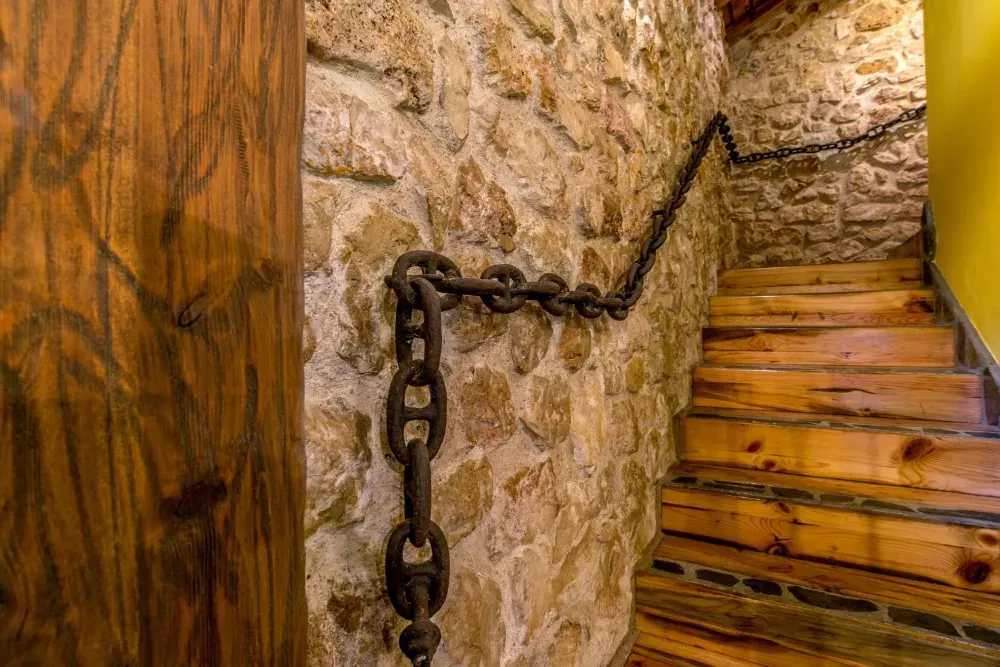 Una escalera de piedra con una pesada barandilla de cadena de hierro, que pasa de un segmento vertical a un ascenso en ángulo.