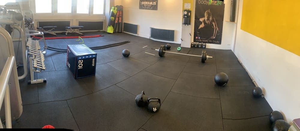 Ein Fitnessstudio mit vielen Gewichten auf dem Boden | bodyfit24