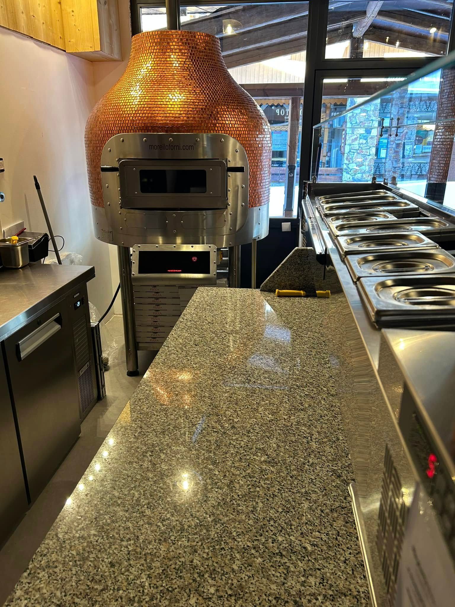 Un comptoir avec saladette et four à pizza