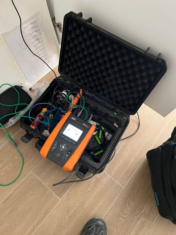 Un estuche negro lleno de un montón de equipos electrónicos se encuentra sobre un piso de madera.