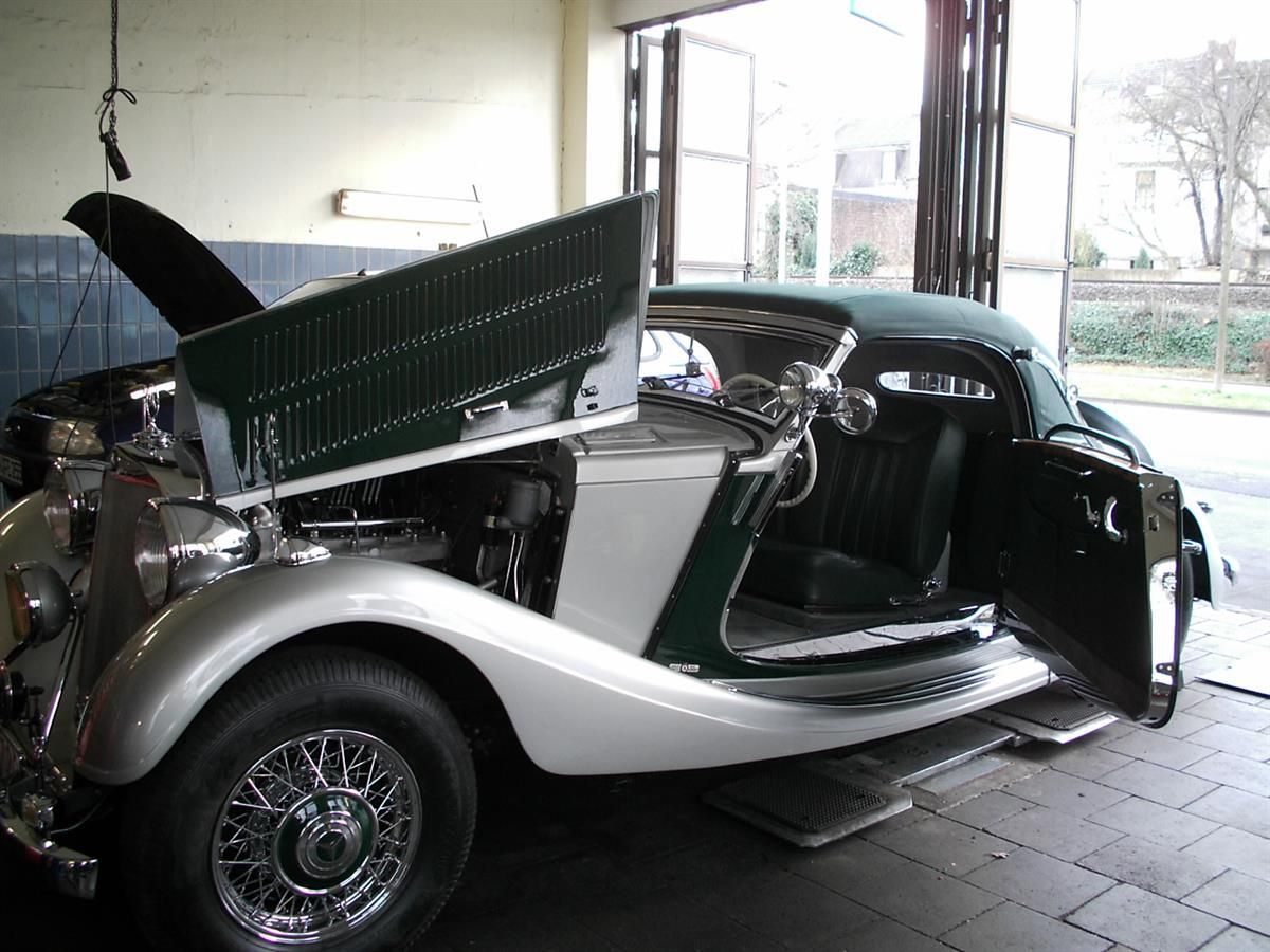 Ein grün-weißes Auto mit geöffneter Motorhaube in einer Garage
