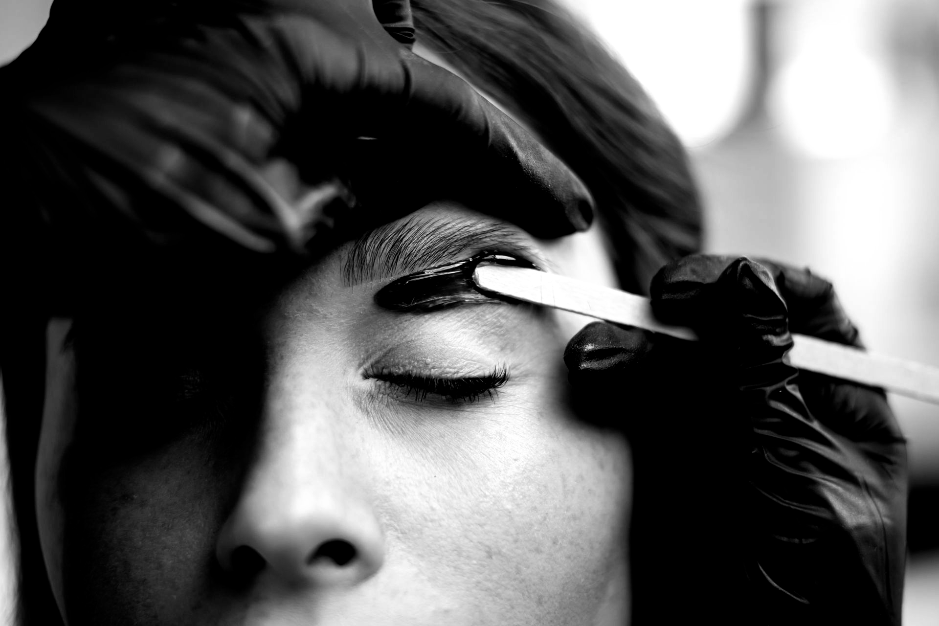 Une estheticienne épile les sourcils d'une femme à la cire.