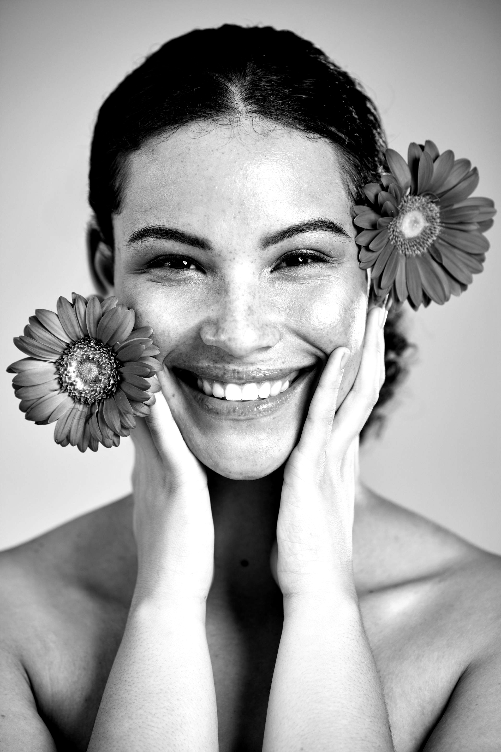 Une femme avec deux fleurs à côté de son visage.