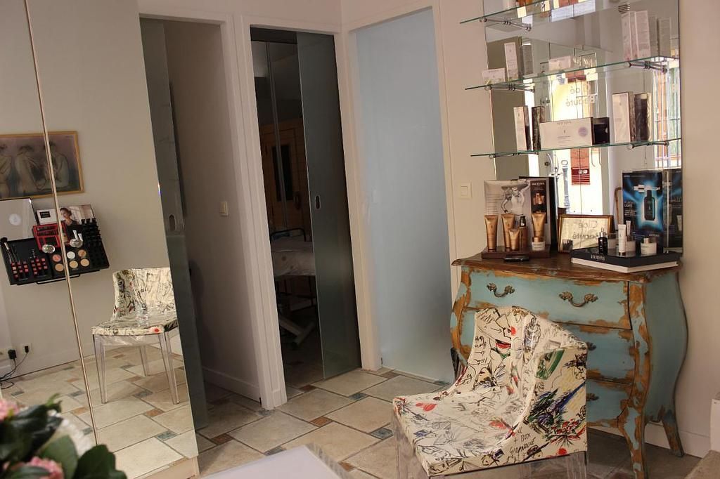 Chambre élégante avec une armoire à miroir, un fauteuil fleuri, une commode ornée et un écran de télévision mural.