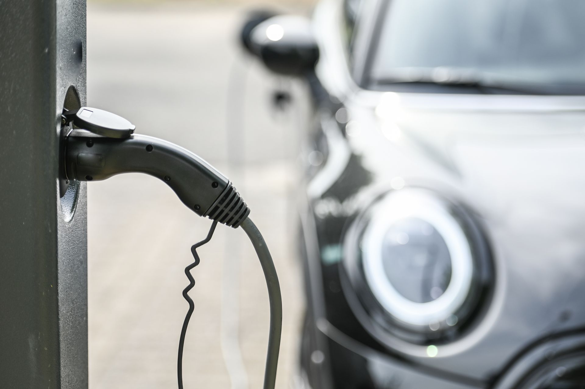 Prise d'une borne de recharge électrique avec une voiture en fond
