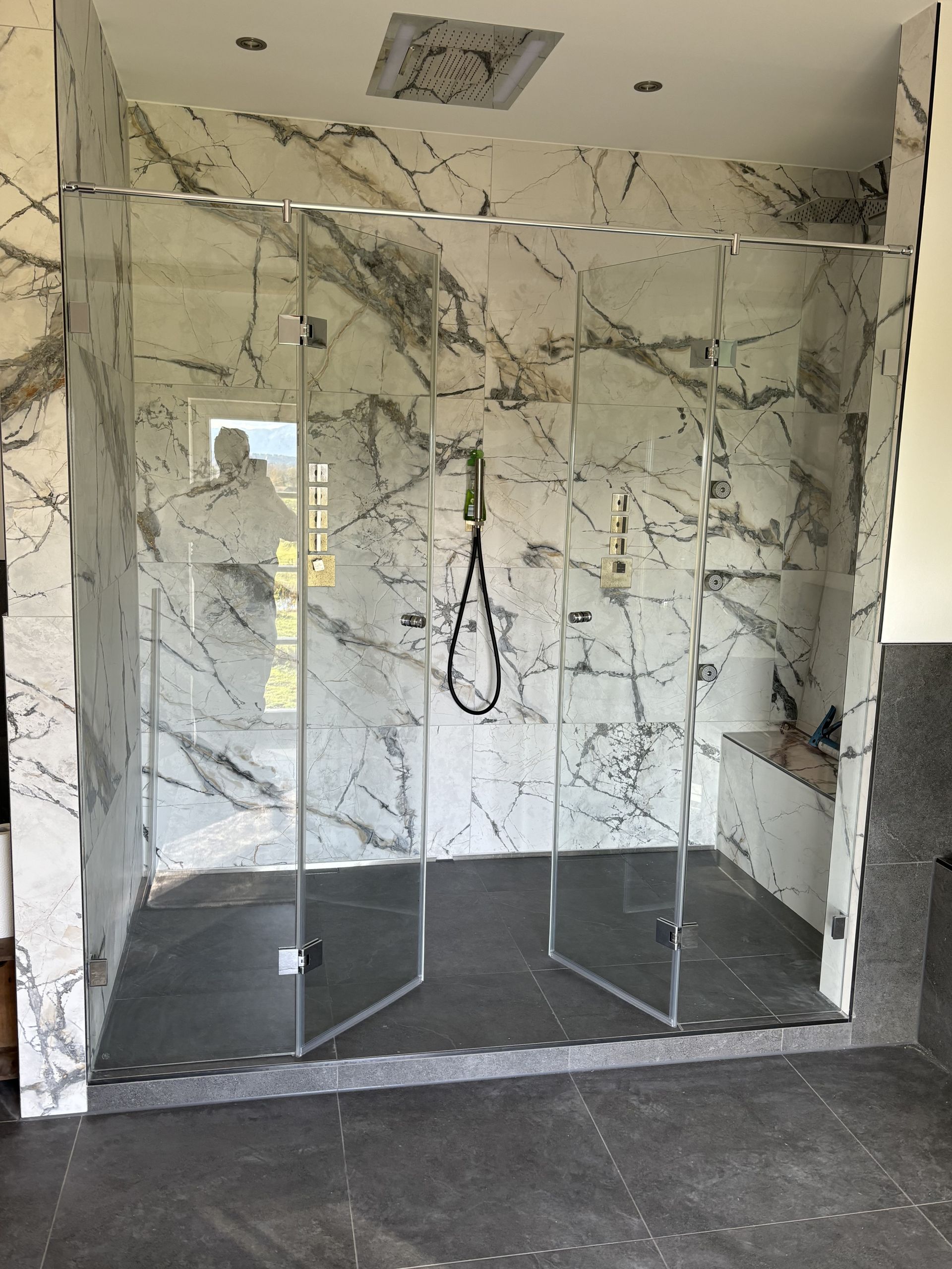 Walk-in-Dusche mit feststehender Glaswand und Regenbrause.