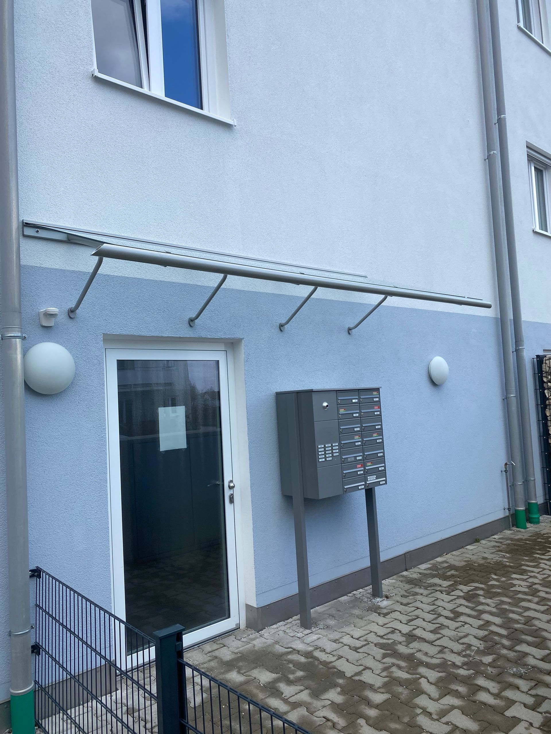 Glasvordach mit Edelstahlhaltern über einer Hauseingangstür.