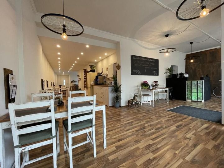 Ein Restaurant mit Holzboden und weißen Tischen und Stühlen. Mom & Son