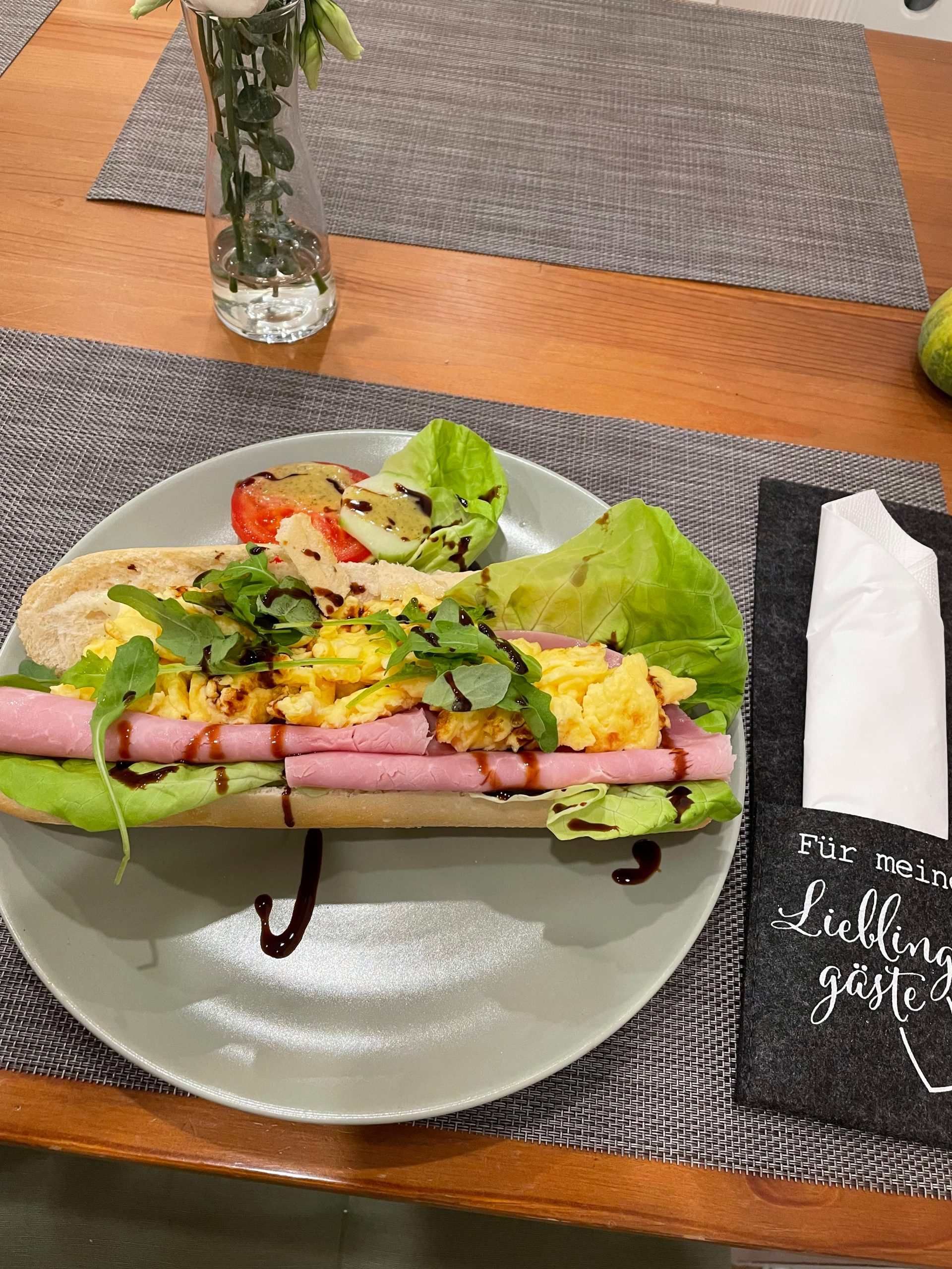 Ein Teller mit Essen auf einem Tisch mit einer Serviette und einer Vase mit Blumen, Mom & Son