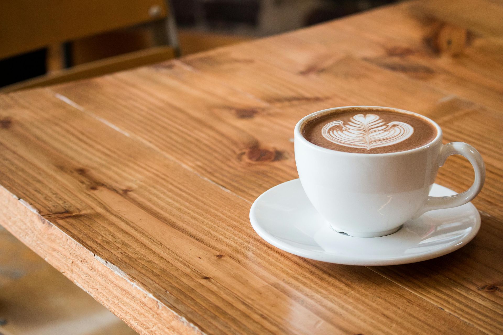 Eine Tasse Kaffee steht auf einer Untertasse auf einem Holztisch.