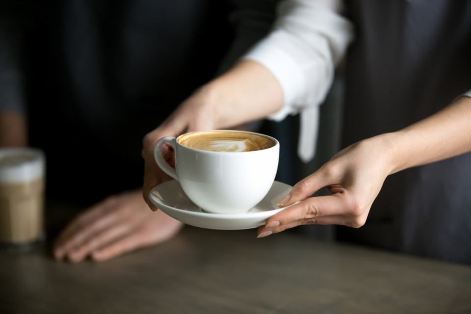 Eine Frau hält eine Tasse Kaffee auf einer Untertasse.