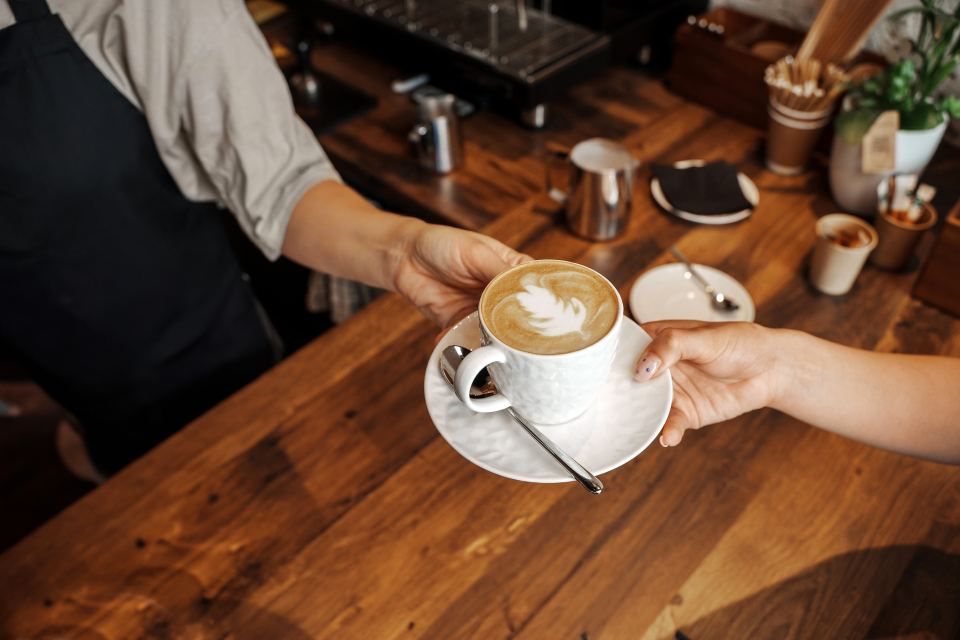 Eine Frau reicht einem Barista eine Tasse Kaffee. Mom & Son
