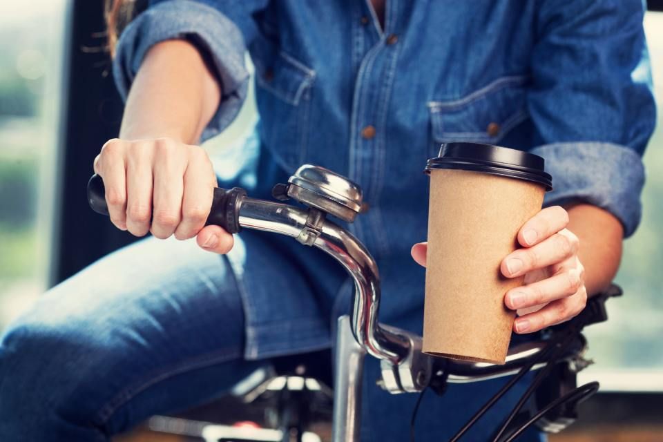 Eine Frau fährt Fahrrad und hält eine Tasse Kaffee, Mom & Son