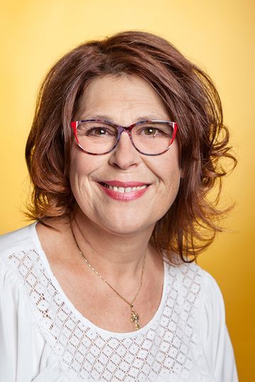 Frau mit braunen Haaren und Brille lächelt