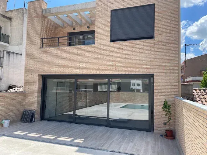 Casa de ladrillo con puertas corredizas de vidrio y vista a la piscina. Balcón en el segundo piso.