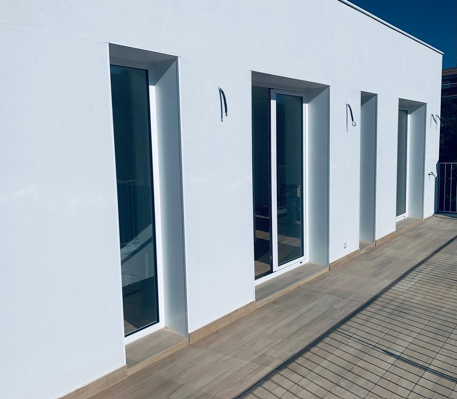 Exterior de edificio blanco con ventanas y pasarela de madera.