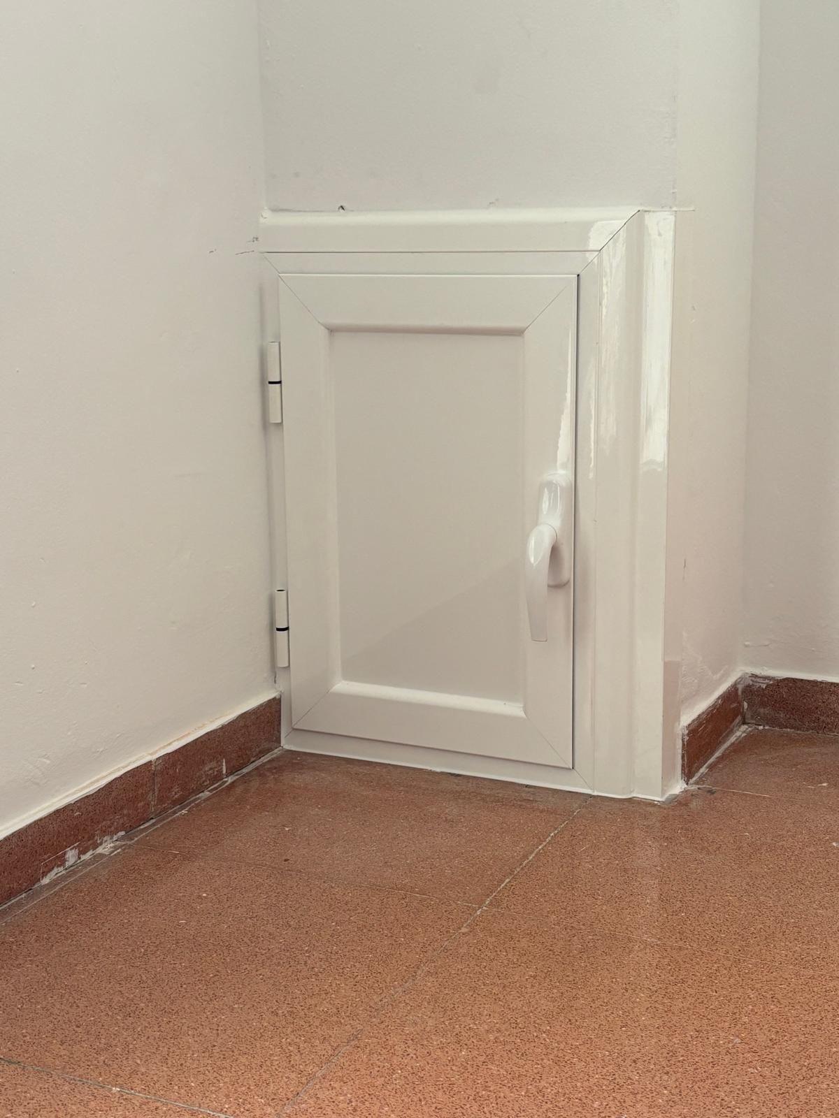 Puerta blanca en esquina, empotrada en la pared, con tirador y bisagras, colocada en marco blanco.
