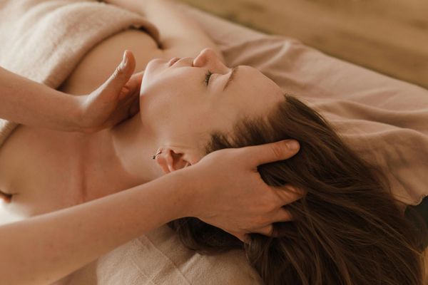 Mujer recibiendo un masaje de cabeza en un spa.