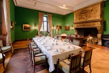 Der Grüne Salon mit einer gedeckten Tafel für eine Veranstaltung im Schlosshotel Hugenpoet in Essen mit historischem Kamin.