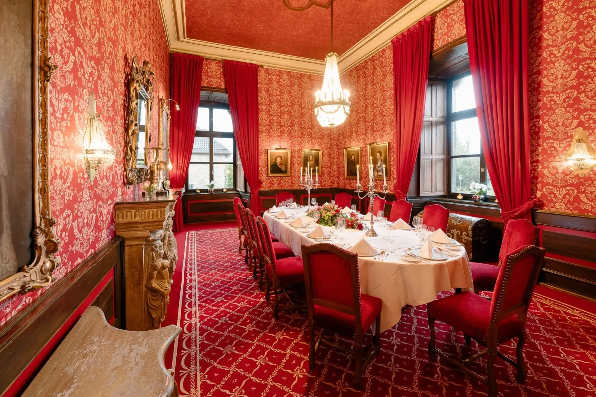 Der Rote Salon mit einer ovalen Tafel für Veranstaltungen und Tagungen im Schlosshotel Hugenpoet